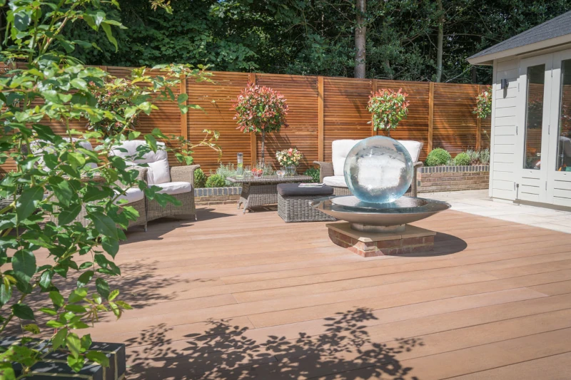 Sunny composite decking area with seating and water feature